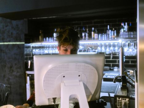 Female restaurant manager working at the reception in the bar of the restaurant with a computer