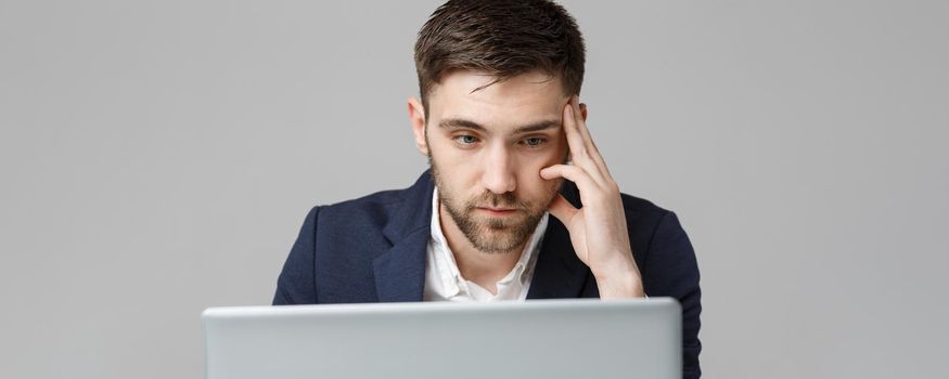 Business Concept - Portrait handsome serious business man in suit looking at laptop. White Background.