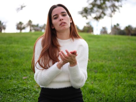 Front view of a young woman in the park clapping sarcastically looking unhappily at the camera. . Concept of emotions.