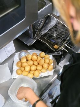 Vertical top view photo of a cook frying fritters with an electric fryer