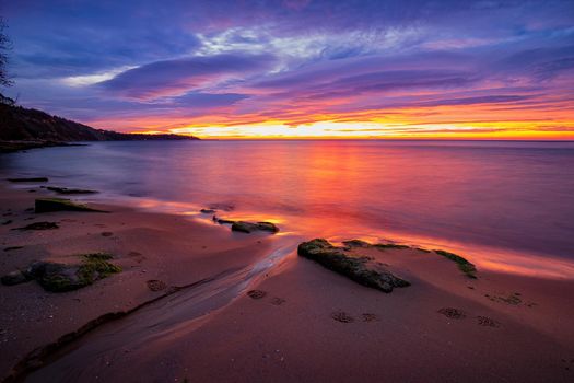 A small brook through sea sand with sky reflection at the morning