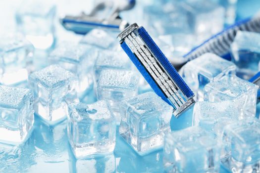 Shaving machine on a blue background with ice cubes. The concept of cleanliness and frosty freshness