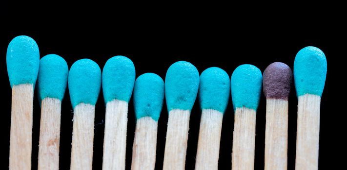 a row of blue matches and one different on black background. Concept