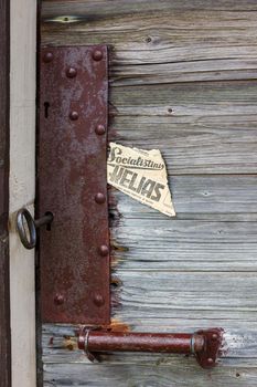 Old lock on wooden door Close-up padlock on old wooden door. The old piece of the newspaper contains the inscription in Lithuanian language - "socialist path"