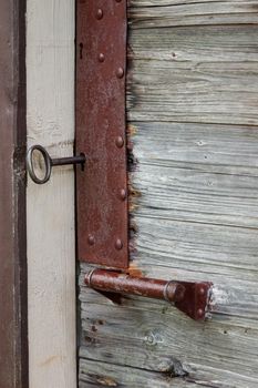 Closeup photo of an old wooden door with a big key and the lock