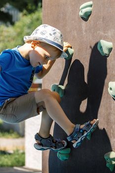 Little boy try to overcome the artificial mountain relief on the street wall for the climbing of the sports ground. the child was able to climb the very top.