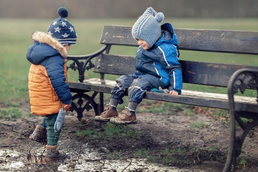 Two little boys is covered in mud and dirt in a swamp at the park. He is very unclean as he learns about nature and outdoors. Both children are happy they don't care to get smeared.