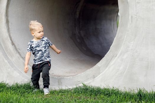 Small boy going out of a grey tunnel. Tunnel view. Destination reached. Running from darkness to light