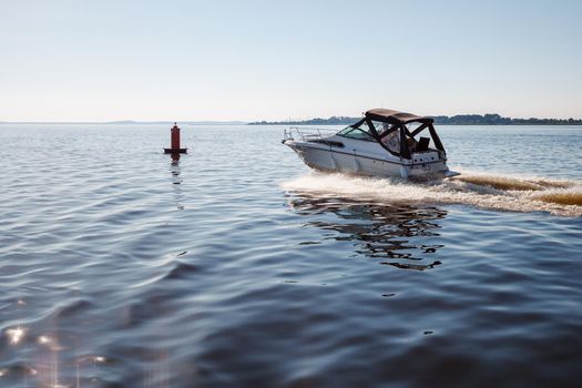 On a summer day, a small boat sails quickly towards the buoy