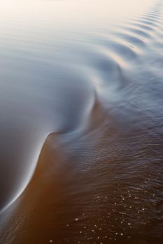 Footprint of the ship. Water twisted by a boat propeller. Beautiful water surface texture. Vertical photo