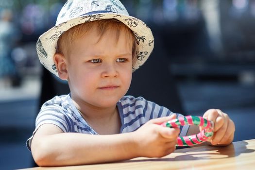 A portrait of a little boy holding a bracelet-shaped candy in his hands. City celebration and happy child.