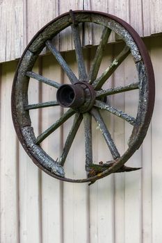 Vintage wooden carriage wheel, wood background. Old wooden carriage wheel hanging on the barn