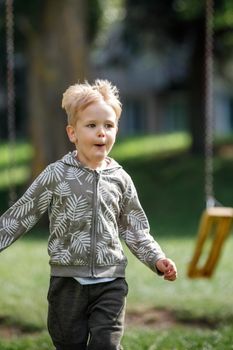 Adorable little boy running outside in slow-motion towards camera happy child runs.