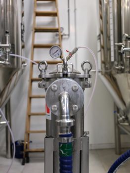 Vertical photo of a barometer connected with tubes to craft beer cylinders at a brewery