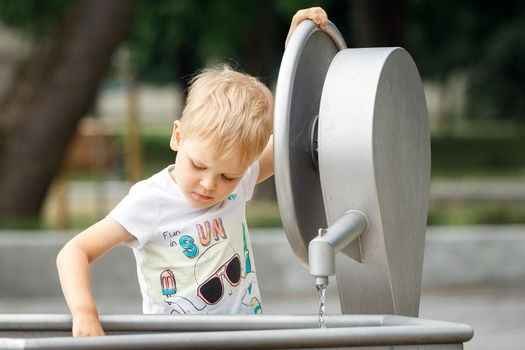 Little boy playing with water tap outdoors.