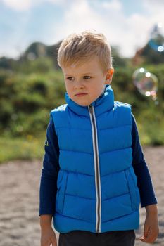 Little boy playing on the fresh air. Unhappy little boy and bubbles.