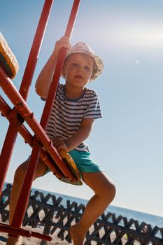 Little boy on a balance swing, in a beach background