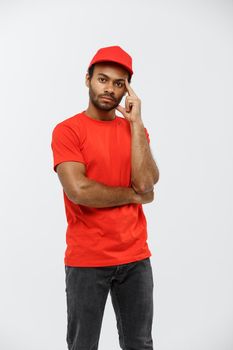 Delivery Concept - Handsome African American delivery man serious thinking of something. Isolated on Grey studio Background. Copy Space