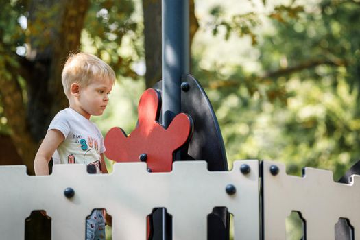 Playing boat captain boy, standing at the red helm or steering wheel of the ship at the colorful playground.