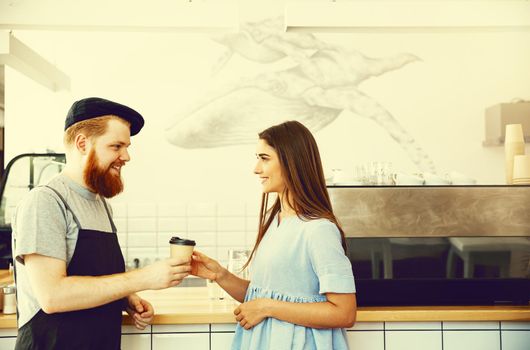 Coffee Business Concept - Positive young bearded man and beautiful attractive lady barista couple in apron.