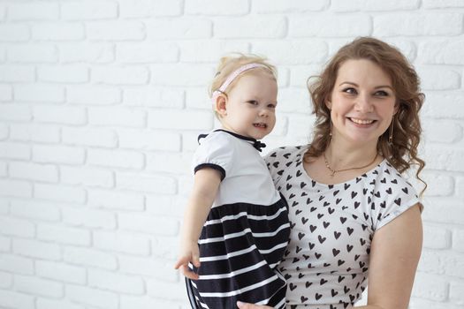 Mother helps her deaf baby daughter putting hearing aid in little girl's ear indoors - cochlear implant and innovative medical technologies