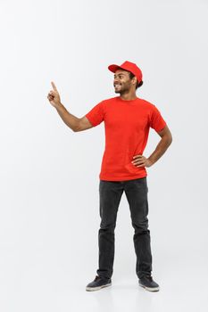 Delivery Concept - Portrait of Happy African American delivery man pointing hand to present something. Isolated on Grey studio Background. Copy Space