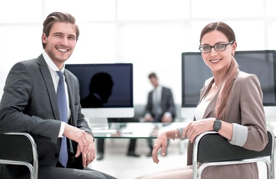 businessman and business woman sitting at office Desk and looking at camera.