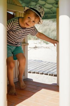 The little boy is hiding in a small plastic playhouse