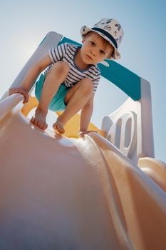 The little boy at the top of the slider not dare to slip down