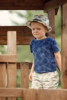 A little boy in a blue shirt on a wooden outdoor playground