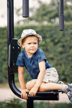 Little child playing on fitness equipment. The little boy goes in for sports on the street exercise machine. Active rest with children.