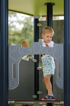 The little boy climbs high up to the playground observation tower.