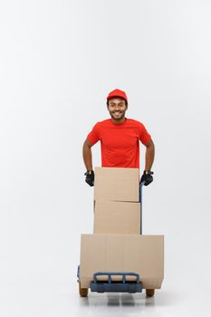 Delivery Concept - Portrait of Handsome African American delivery man or courier pushing hand truck with stack of boxes. Isolated on Grey studio Background. Copy Space