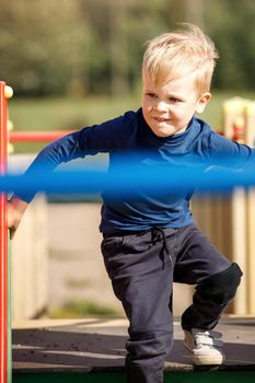 A naughty, very agile boy actively runs through the labyrinths of an outdoor playground.