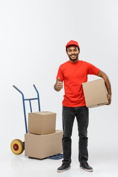 Delivery Concept - Portrait of Handsome African American delivery man or courier with hand truck and holding box. Isolated on Grey studio Background. Copy Space