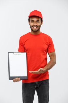 Delivery Concept - Portrait of Handsome African American delivery man or courier showing a confirmation document form to sign. Isolated on Grey studio Background. Copy Space