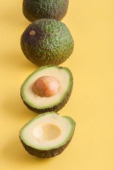 avocado whole and half on yellow background. High quality photo