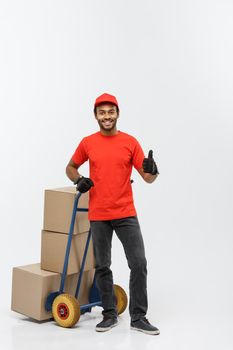 Delivery Concept - Portrait of Handsome African American delivery man or courier pushing hand truck with stack of boxes. Isolated on Grey studio Background. Copy Space