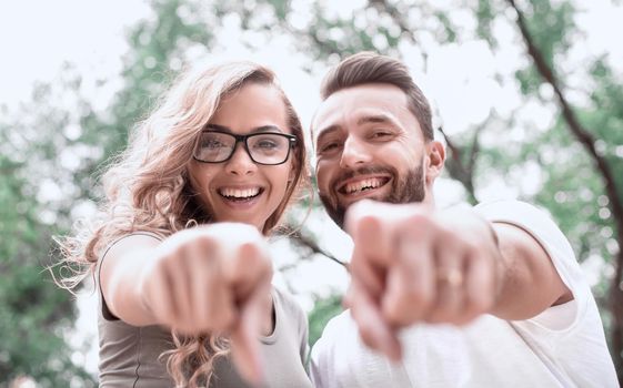 close up.happy newlyweds standing in the Park and pointing at you.photo with copy space