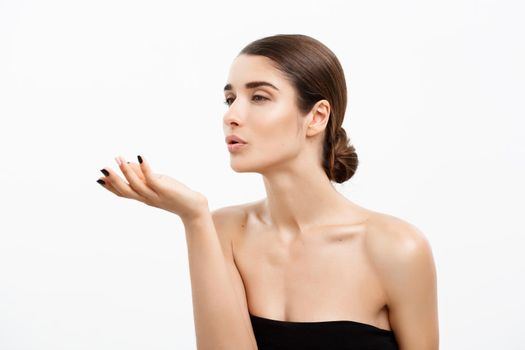 Health care and spa concept - attractive young and healthy woman blowing a kiss from her hand white background