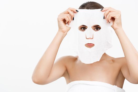 Beauty Skin Care Concept - Beautiful Caucasian Woman applying paper sheet mask on her face white background