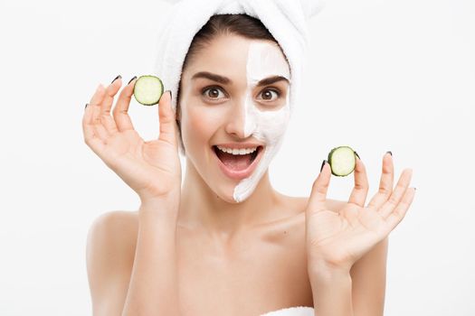 Beauty Youth Skin Care Concept - Portrait Beautiful Caucasian Woman apply cream and holding fresh cucumber in front of her face.Isolated over white background