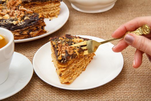 Female hand holding a fork and going to taste homemade chocolate cake lying on white saucer