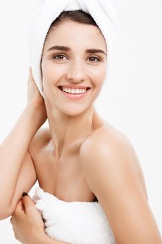 Beauty and Skin care concept - Beautiful caucasian Young Woman with bath towel on head covering her breasts, on white touching her skin