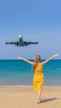 Woman have fun on the beach watching the landing planes. Traveling on an airplane concept. Text space. Island Phuket in Thailand. Impressive paradise. Hot beach Mai Khao. Amazing landscape. VERTICAL FORMAT for Instagram mobile story or stories size. Mobile wallpaper