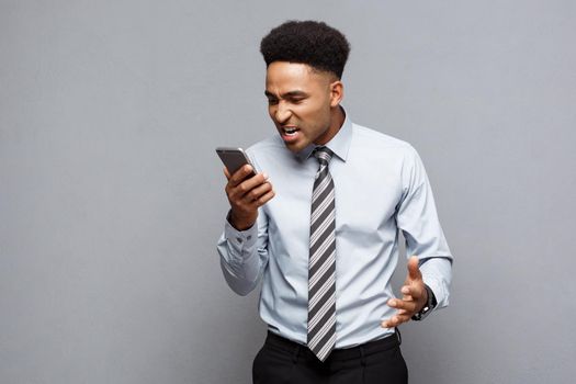 Business Concept - Stressful african american businessman shouting and screaming on mobile phone