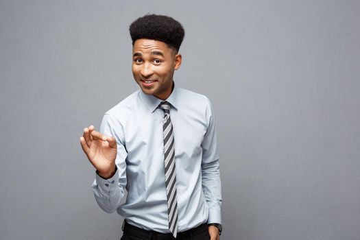 Business Concept - Confident cheerful young African American showing ok finger in front of him with surprising expression over grey background