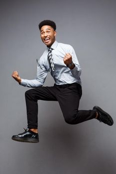 Business Concept - Full length portrait of successful african american businessman happy jumping in the office