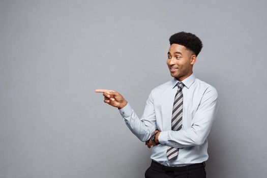 Business Concept - Confident thoughtful young African American pointing finger on side over grey background