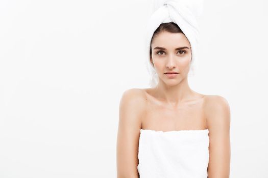 Beauty and Skin care concept - Beautiful caucasian Young Woman with bath towel on head covering her breasts, on white.